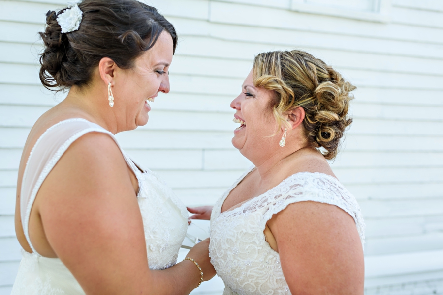 Two brides laughing with excitement on their wedding day.